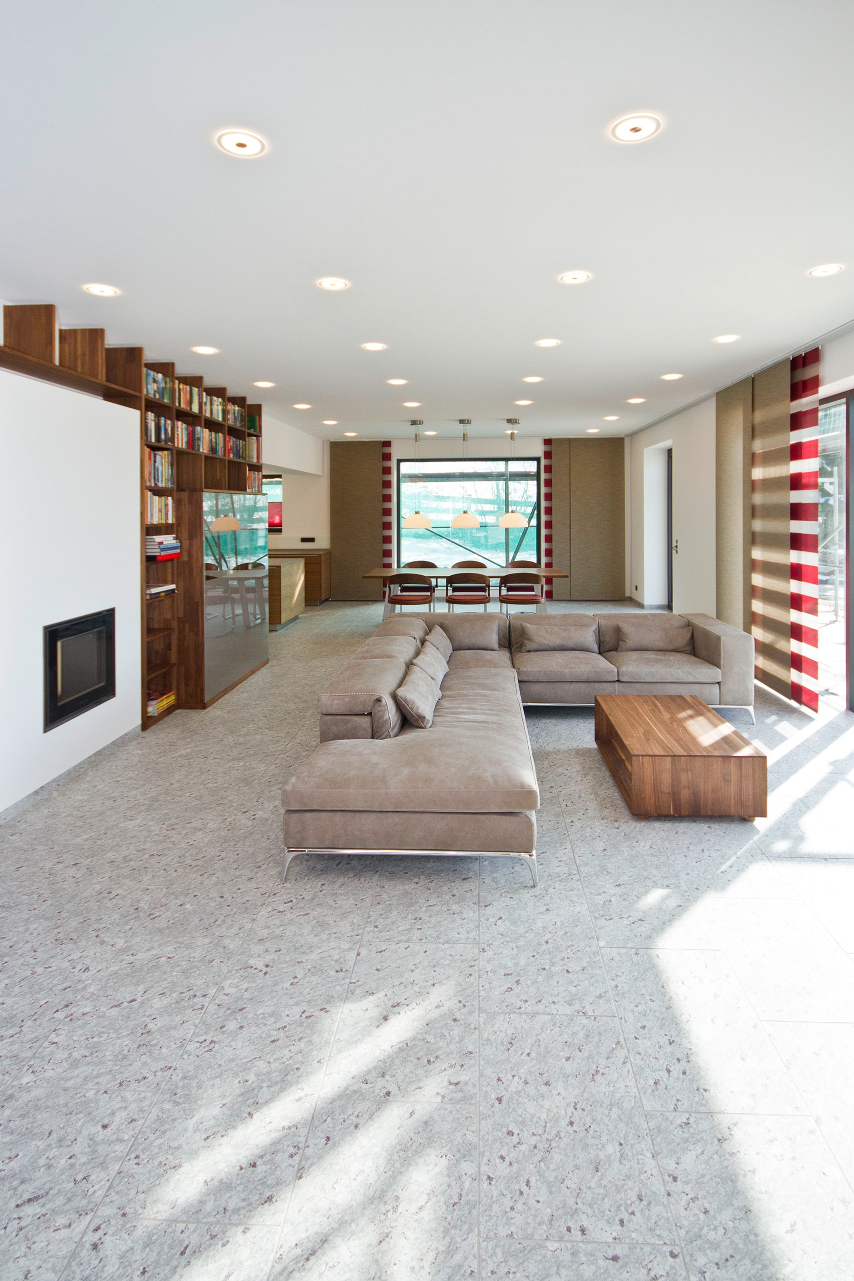Wohnzimmer mit Bodenbelag aus hellem Naturstein Blossom White, Ecksofa und Bücherwand