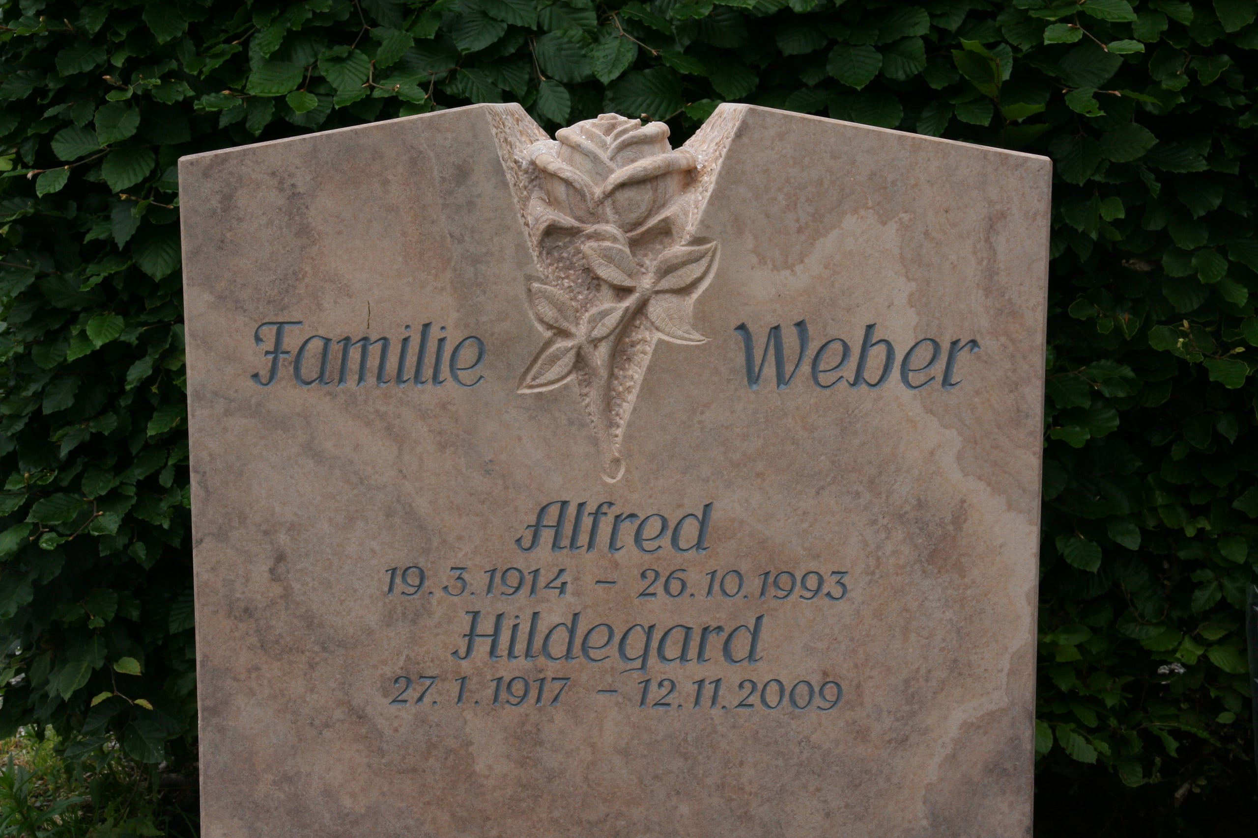 Grabstein aus Naturstein Rainbow-Sandstein mit gemeißelter Rose und Inschrift „Familie Weber"